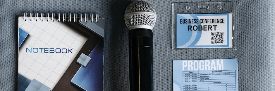 Flat lay of conference essentials including microphone, notebook, and program.