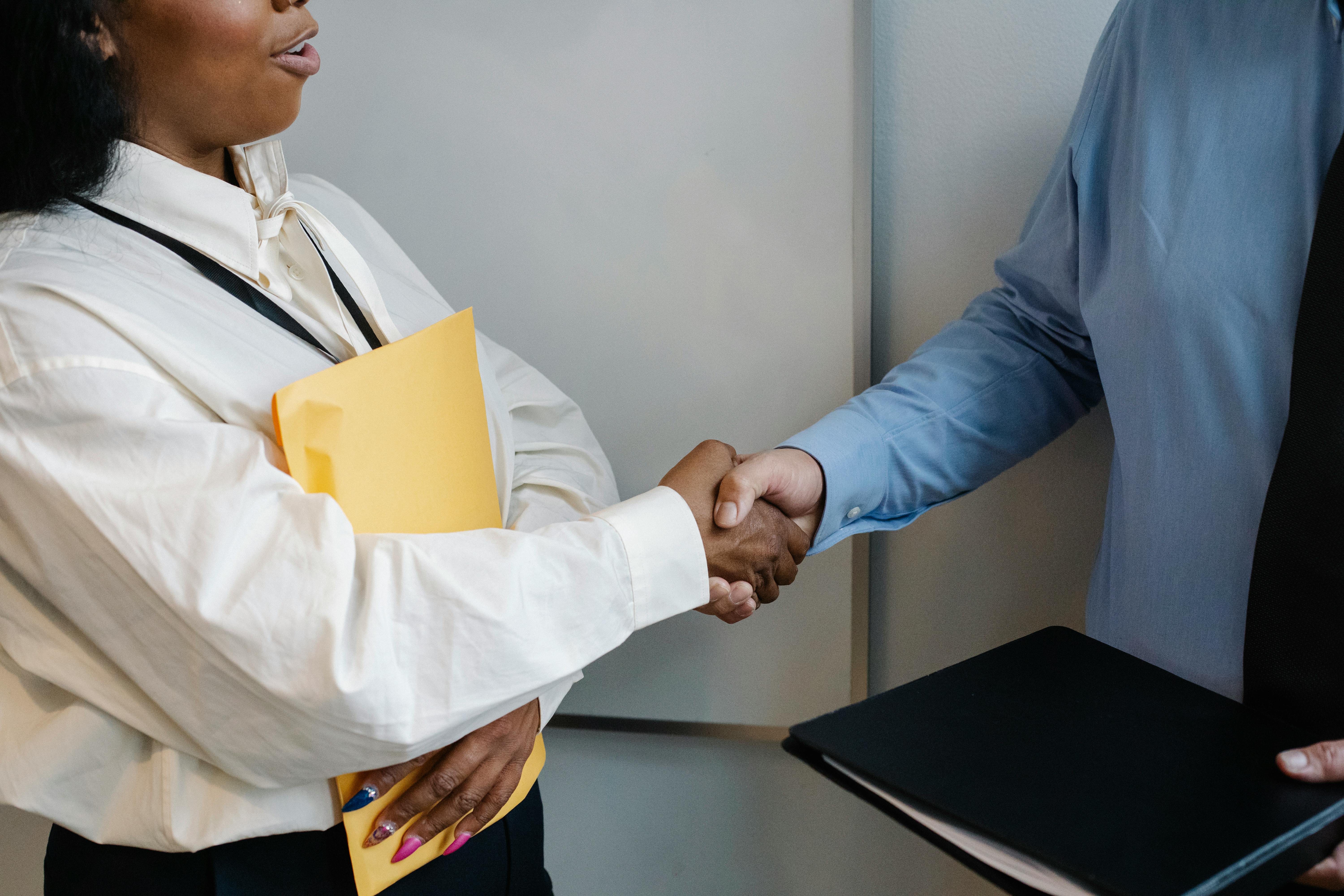 Two professionals shaking hands in an office setting, symbolizing agreement.