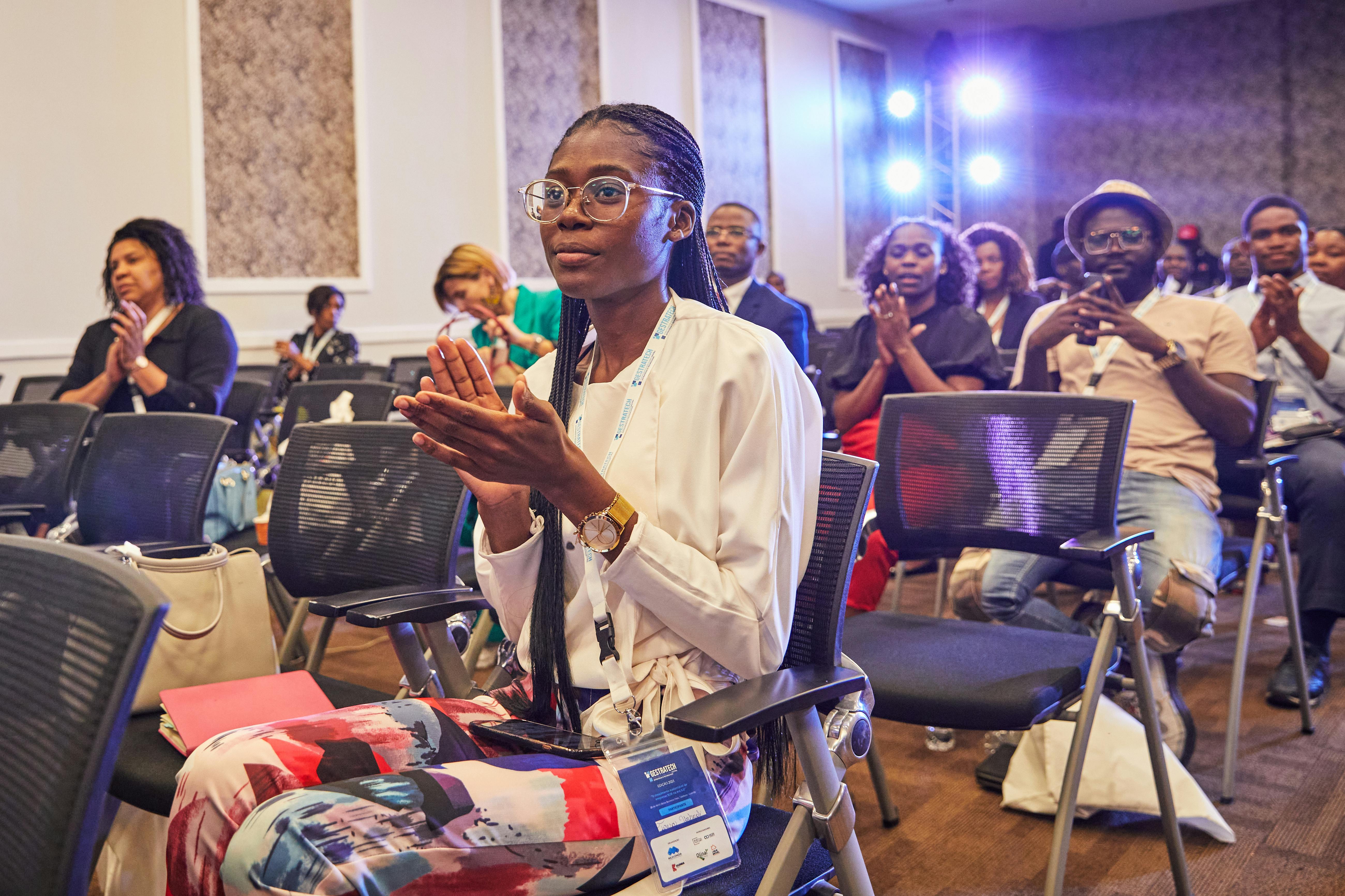 A diverse group of people clapping at an indoor business conference.